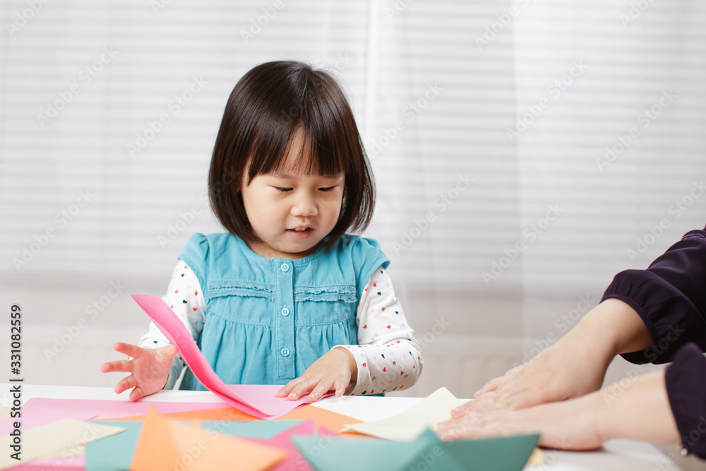toddler girl learn making Origami at home against white background toddler girl learn making Origami at home against white background