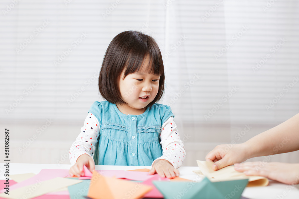 toddler girl learn making Origami at home against white background toddler girl learn making Origami at home against white background