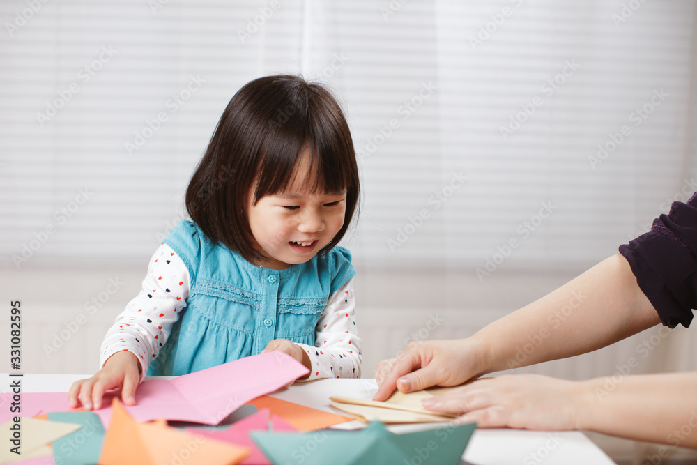 toddler girl learn making Origami at home against white background toddler girl learn making Origami at home against white background
