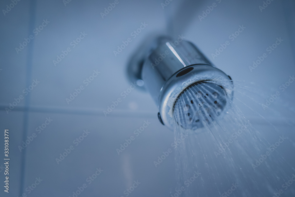 Dirty shower head wirth spraying water out of it. Dirty shower in a bathroom, lime or limestone residue visible around the nozzles. Dirty shower head wirth spraying water out of it. Dirty shower in a bathroom, lime or limestone residue visible around the nozzles.