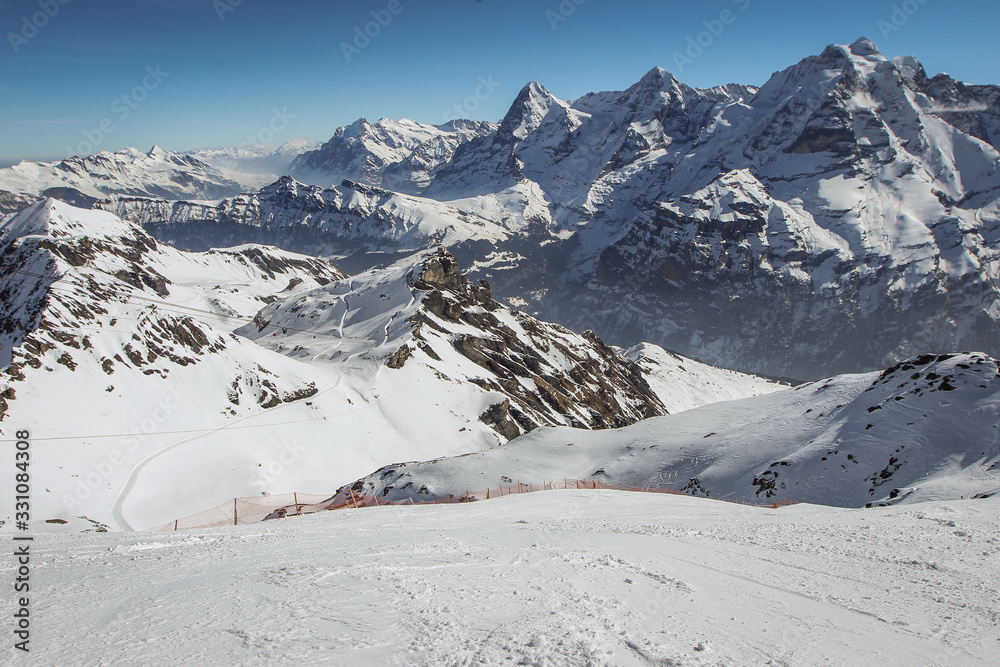 Beautiful alpine panorama on a sunny day from the top of Schilthorn, Switzerland, peak above Murren. Gorgeous landscape in switzerland with steep skiing slope Beautiful alpine panorama on a sunny day from the top of Schilthorn, Switzerland, peak above Murren. Gorgeous landscape in switzerland with steep skiing slope