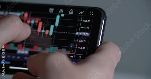 Wallpaper Mural Investor watching the change of stock market on a phone Torontodigital.ca