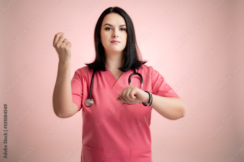 Beautiful woman doctor with stethoscope, wearing pink scrubs showing time is money