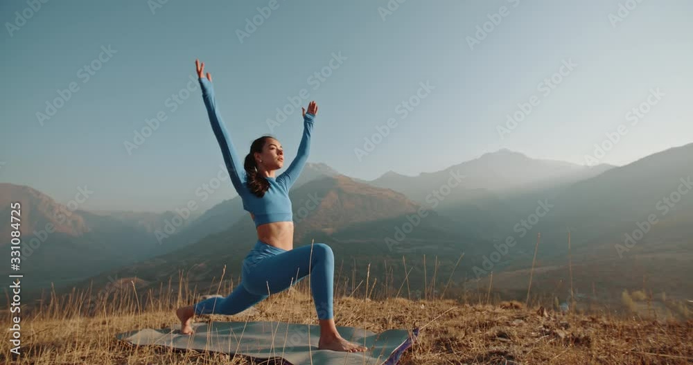 Yoga session in mountains. Young athletic girl training in cliffy mountains during sunrise, doing various yoga poses - healthy lifestyle concept 4k footage