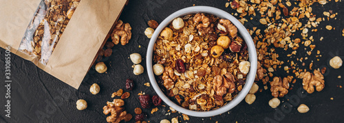 a delicious and crunchy oatmeal granola with honey, nuts, dried fruits and grains is poured out of the praml package into a plate. food photography background