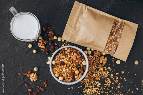 a delicious and crunchy oatmeal granola with honey, nuts, dried fruits and grains is poured out of the praml package into a plate. food photography background