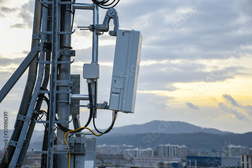 5G new radio telecommunication network antenna mounted on a metal pole providing strong signal waves from the top of the roof across big city 
