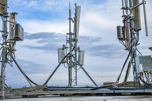 Cellular radio telecommunication network antenna mounted on a metal pole providing strong signal waves from the top of the roof across big city 