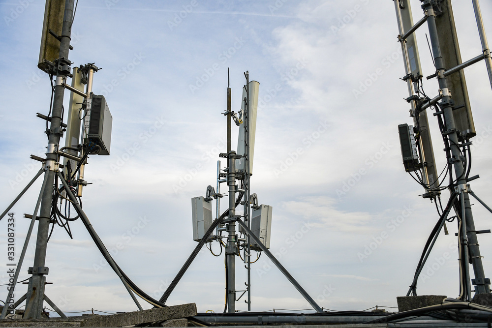 Cellular radio telecommunication network antenna mounted on a metal pole providing strong signal waves from the top of the roof across big city Cellular radio telecommunication network antenna mounted on a metal pole providing strong signal waves from the top of the roof across big city