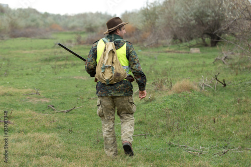 Hunting period  autumn season open. A hunter with a gun in his hands in hunting clothes in the autumn forest in search of a trophy. A man stands with weapons and hunting dogs tracking down the game.