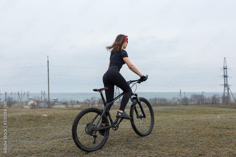 Girl on a mountain bike on offroad, beautiful portrait of a cyclist in rainy weather, Fitness girl rides a modern carbon fiber mountain bike in sportswear. Close-up portrait of a girl in red bandana. Girl on a mountain bike on offroad, beautiful portrait of a cyclist in rainy weather, Fitness girl rides a modern carbon fiber mountain bike in sportswear. Close-up portrait of a girl in red bandana.