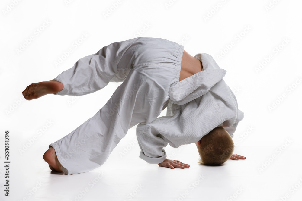 Judo boy doing warm-up spinning around himself while standing on his head Judo boy doing warm-up spinning around himself while standing on his head