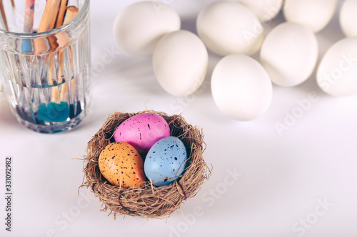 Easter eggs in the nest and tools for painting near by
