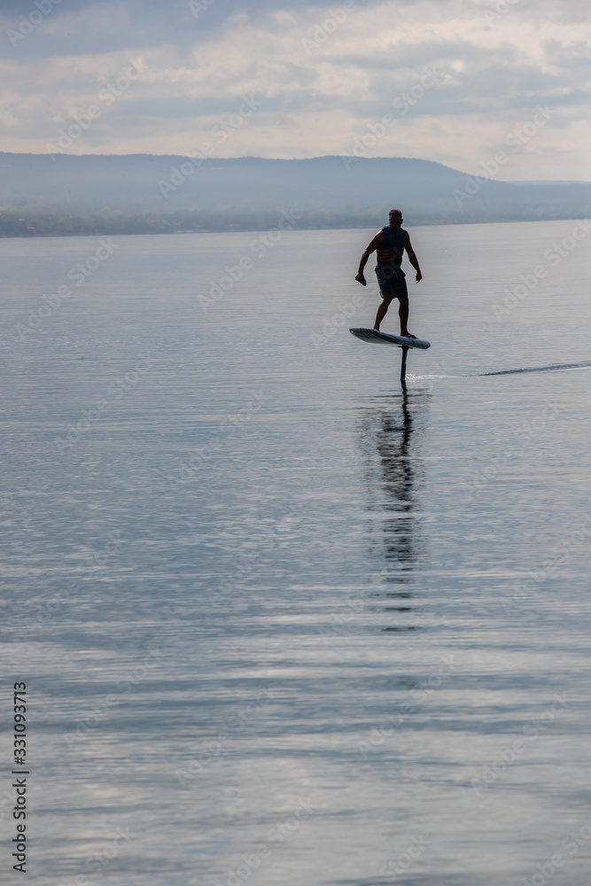 Man riding an electric hydrofoil foil board on a lake with a life jacket