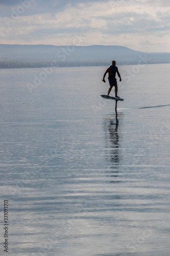 Obraz na płótnie Man riding an electric hydrofoil foil board on a lake with a life jacket w salonie