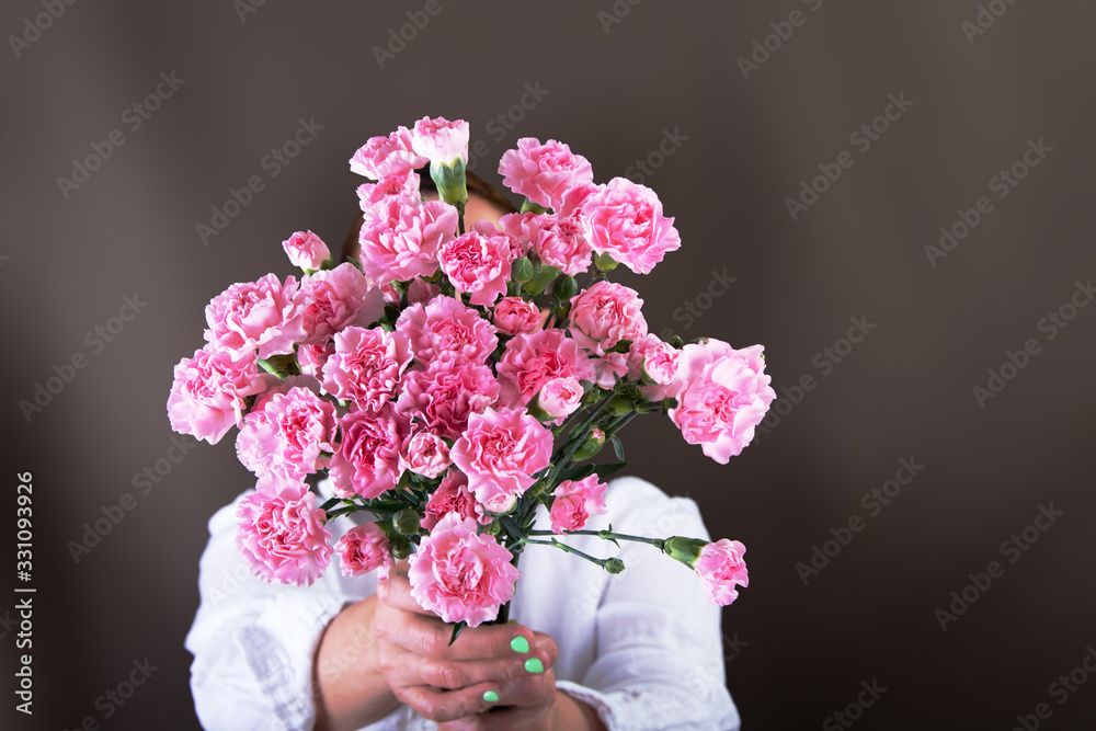 Woman holding a bouquet of pink carnations  in her hand..
