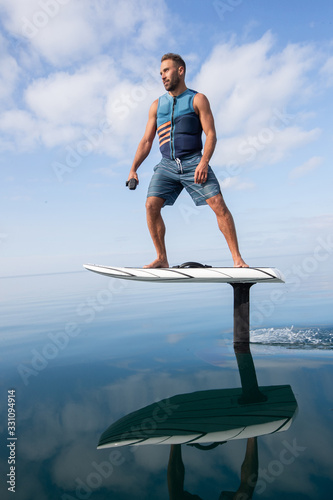Obraz na płótnie Man riding an electric hydrofoil foil board on a lake with a life jacket w salonie