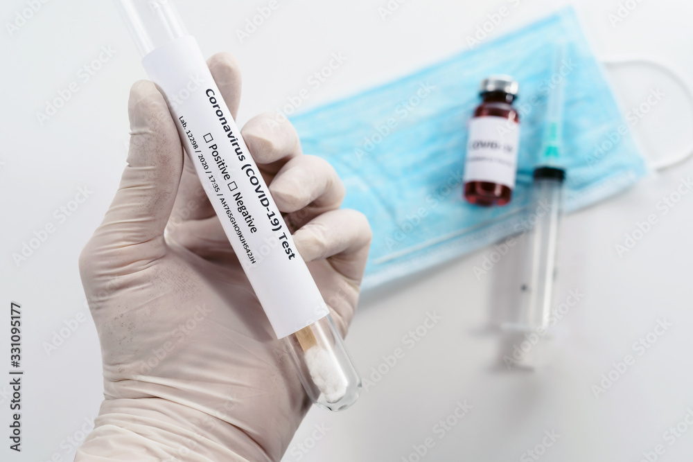 doctor’s hands holding a test tube with biological material or DNA of human infected with coronavirus. Vaccine and syringe at soft-focus. White background isolated close up doctor’s hands holding a test tube with biological material or DNA of human infected with coronavirus. Vaccine and syringe at soft-focus. White background isolated close up