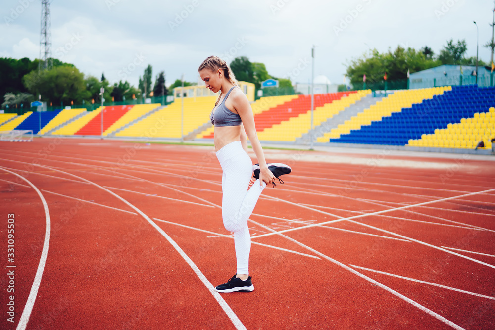 Fototapeta premium Sporty woman stretching at stadium