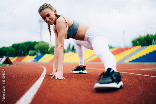 Sporty woman stretching legs in stadium