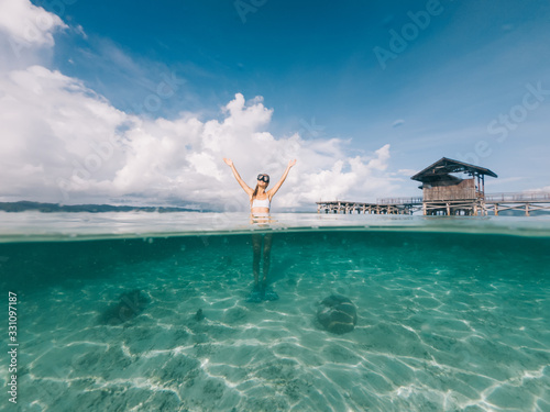 Young blonde with raised hands standing on sea shallow