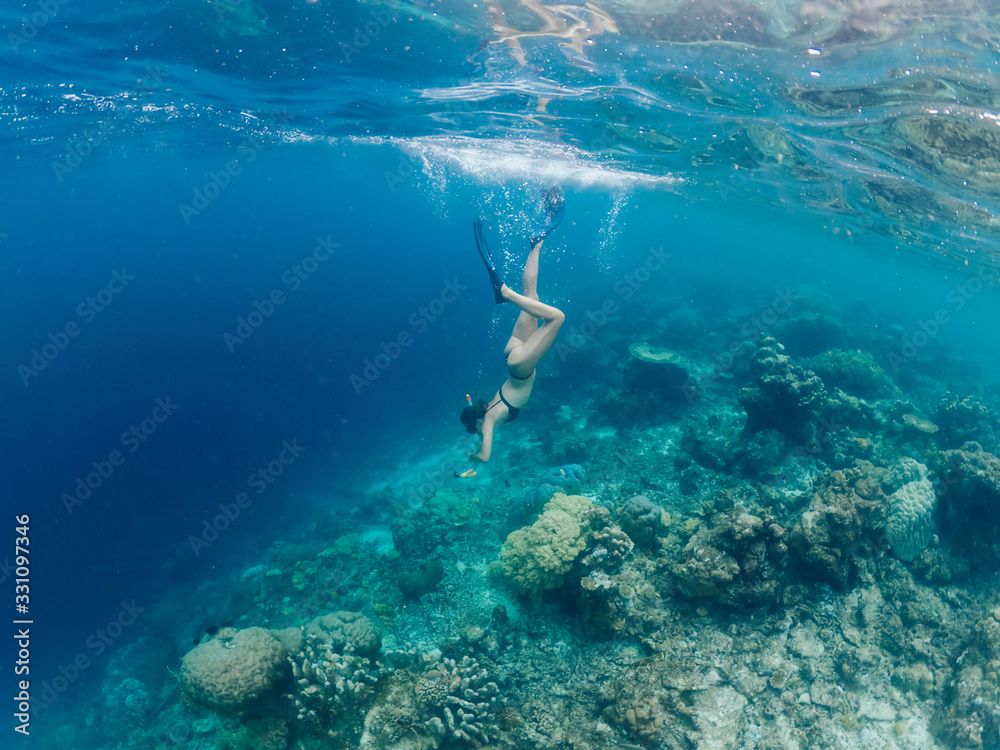 Woman scuba diver in flippers snorkeling down for recreation during aqua adventure in underwater world with coral reefs, female discovering natural environment of Thailand enjoying active trip