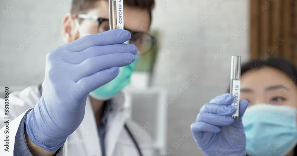 Two Doctors with protective gloves holding testing samples on Coronavirus. Chinese scientists are exploring New Pandemic`s Virus, Covid-19. Doctors in China using Protection, making COVID Tests. Two Doctors with protective gloves holding testing samples on Coronavirus. Chinese scientists are exploring New Pandemic`s Virus, Covid-19. Doctors in China using Protection, making COVID Tests.