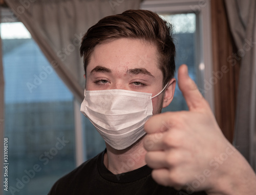 teen wearing a face mask gives thumbs up