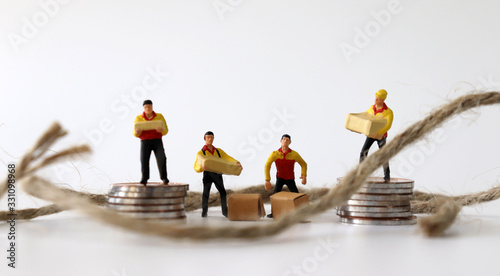 Miniature courier and rope standing on a pile of coins.