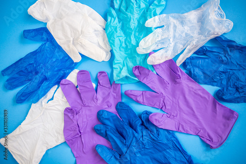 Pile of multicolored multiple medical latex gloves top view on a blue background. Coronavirus protection.