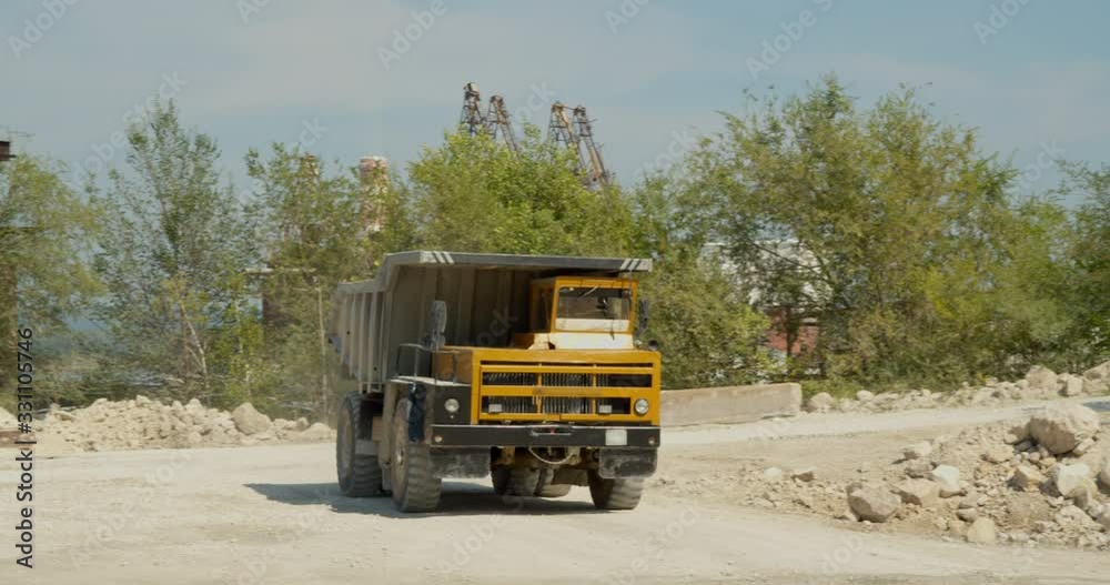 A huge mining truck after unloading goes to the quarry for the rock. In the background is a mining company that processes rock. A huge mining truck after unloading goes to the quarry for the rock. In the background is a mining company that processes rock.