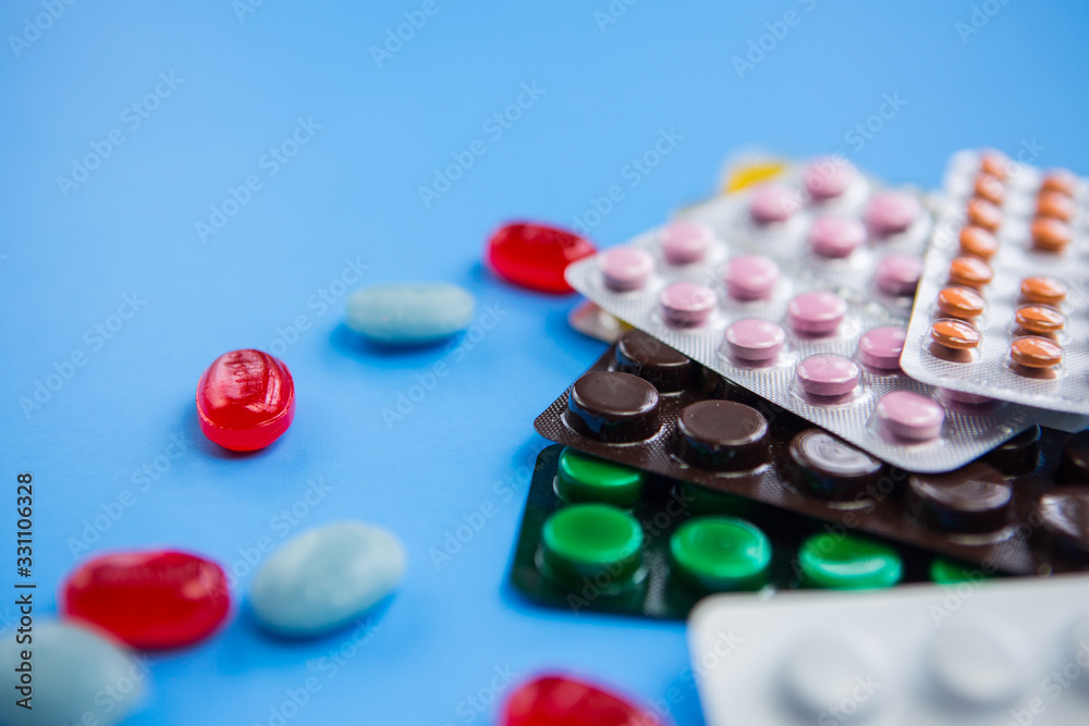 Flat lay composition with bunch of different colorful pills and blister packs in the corner. Pile of unpacked medication on paper textured background. Close up, copy space. Flat lay composition with bunch of different colorful pills and blister packs in the corner. Pile of unpacked medication on paper textured background. Close up, copy space.