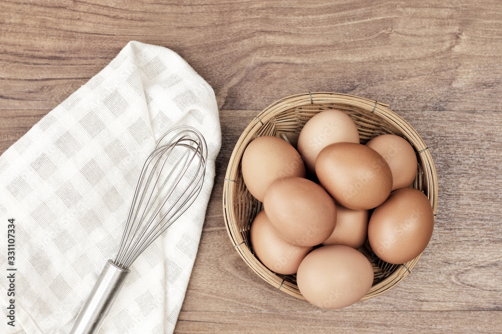 Top view of raw eggs in the basket and Straw or chaff with Egg beater , hand towel on wooden table. Top view of raw eggs in the basket and Straw or chaff with Egg beater , hand towel on wooden table.