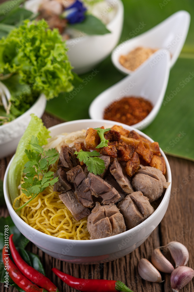 Yellow noodles in a cup with crispy pork, slices of pork, and meatballs together with Thai food-style noodles Yellow noodles in a cup with crispy pork, slices of pork, and meatballs together with Thai food-style noodles