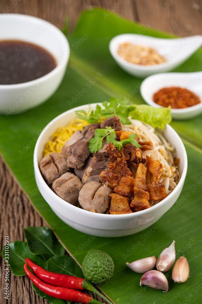 Yellow noodles in a cup with crispy pork, slices of pork, and meatballs together with Thai food-style noodles Yellow noodles in a cup with crispy pork, slices of pork, and meatballs together with Thai food-style noodles