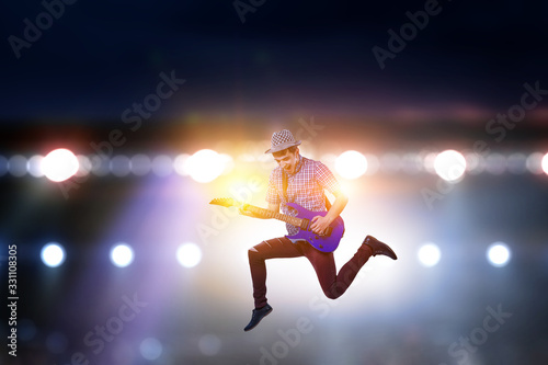 Passionate guitarist with hat jumps