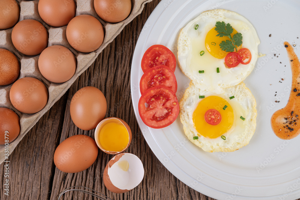 Fried egg on a white plate with sliced ​​Spring onion and sliced ​​tomatoes