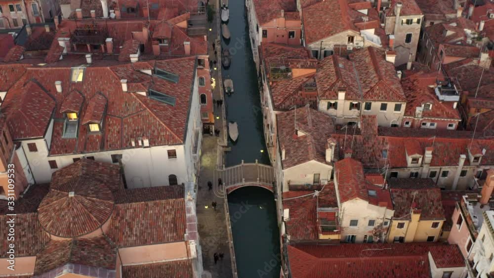 Aerial, drone shot tilting over people walking on a bridge, at a small channel, Venetian streets, on a evening, in Venice city, Italy Aerial, drone shot tilting over people walking on a bridge, at a small channel, Venetian streets, on a evening, in Venice city, Italy