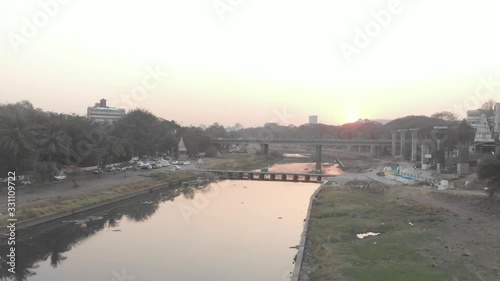 Rising drone shot over a river going through a city at sunset photo