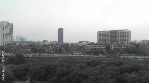 Follow drone shot of local Mumbai train with the city in the background photo