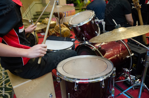 Unidentified Asian boy play drum set in music room