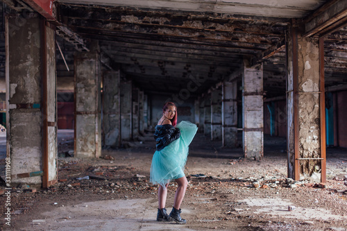 Portrait of a young girl with pink hair standing inside of collapsed building surrounded by ruins
