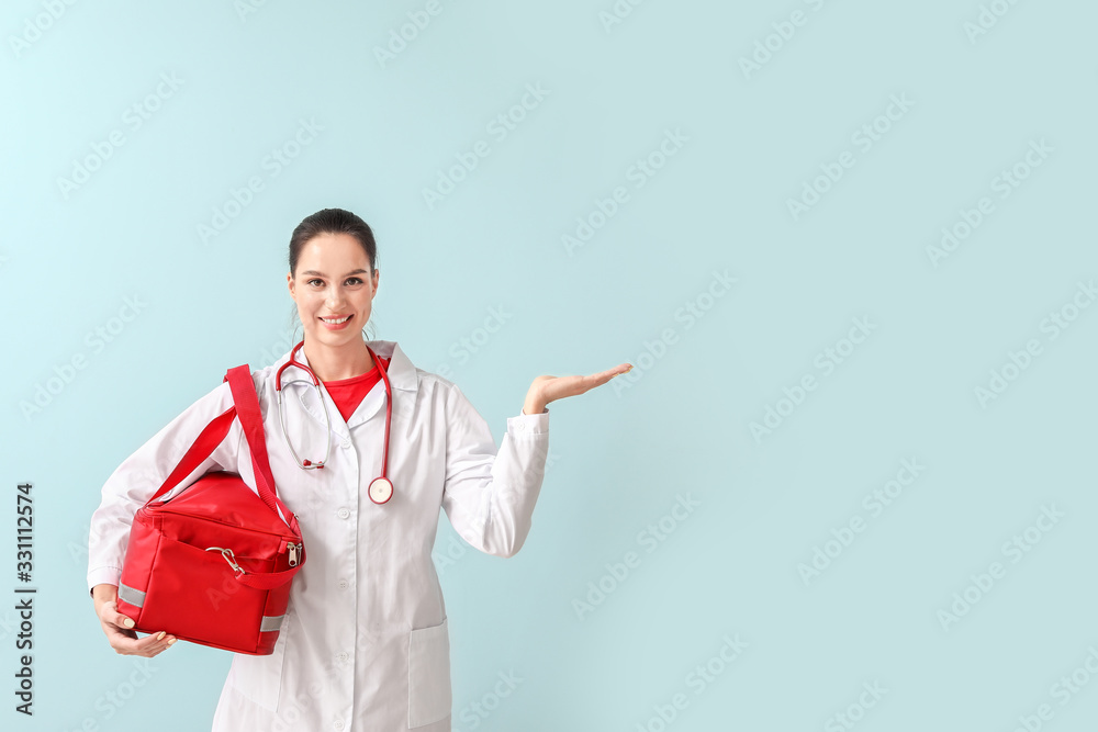 Female paramedic with bag showing something on color background Female paramedic with bag showing something on color background
