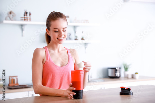Sporty young woman making protein shake at home photo