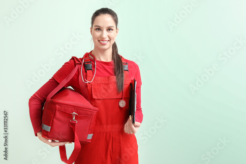 Female paramedic with bag on color background photo