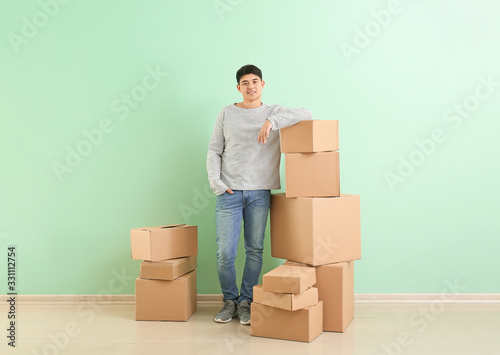 Asian man with moving boxes near color wall