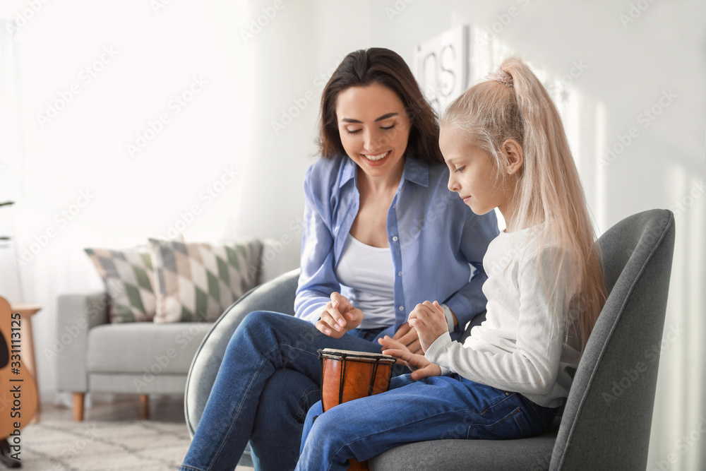 Private music teacher giving lessons to little girl at home Private music teacher giving lessons to little girl at home