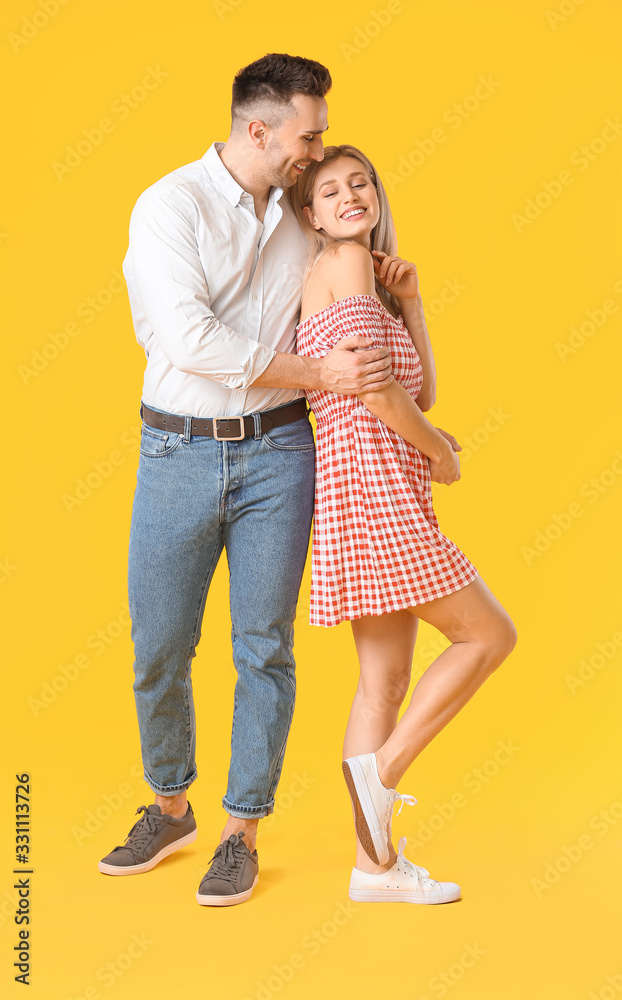 Happy dancing young couple on color background