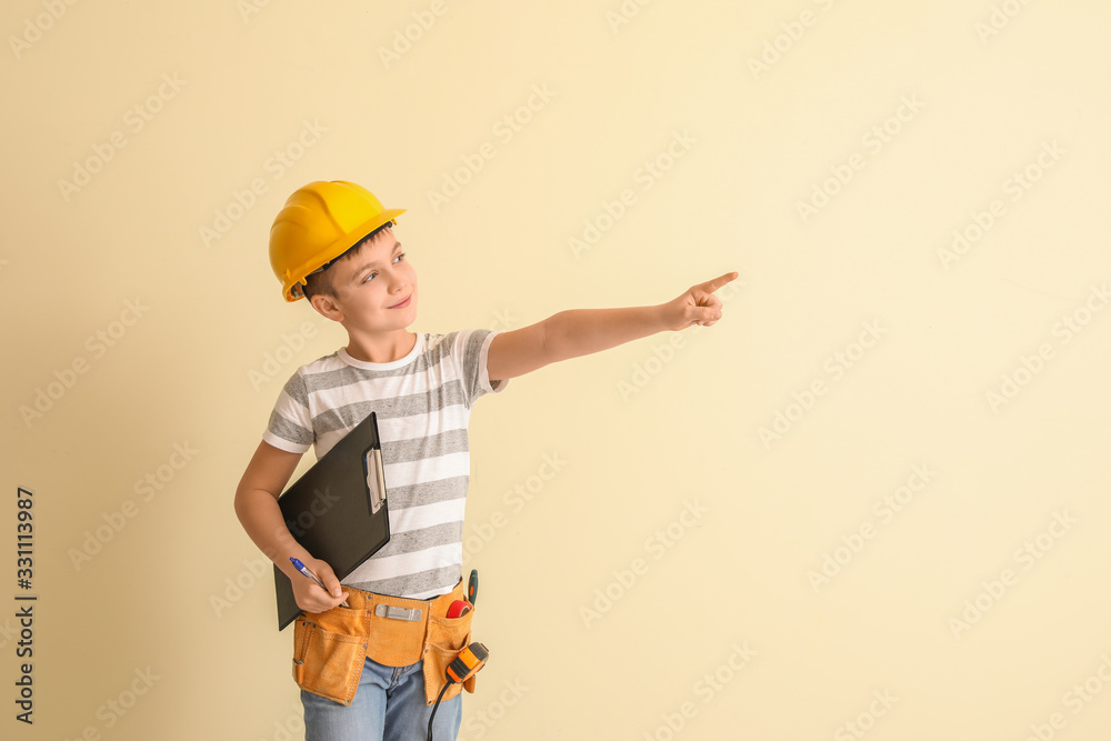 Cute little architect pointing at something on light background Cute little architect pointing at something on light background