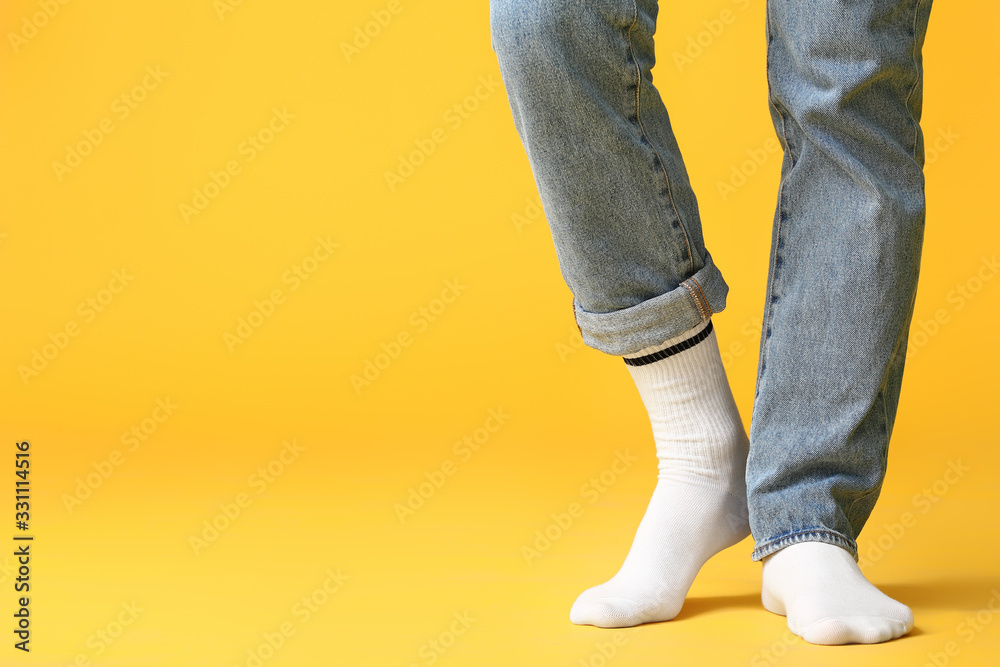 Male legs in socks and jeans on color background Male legs in socks and jeans on color background